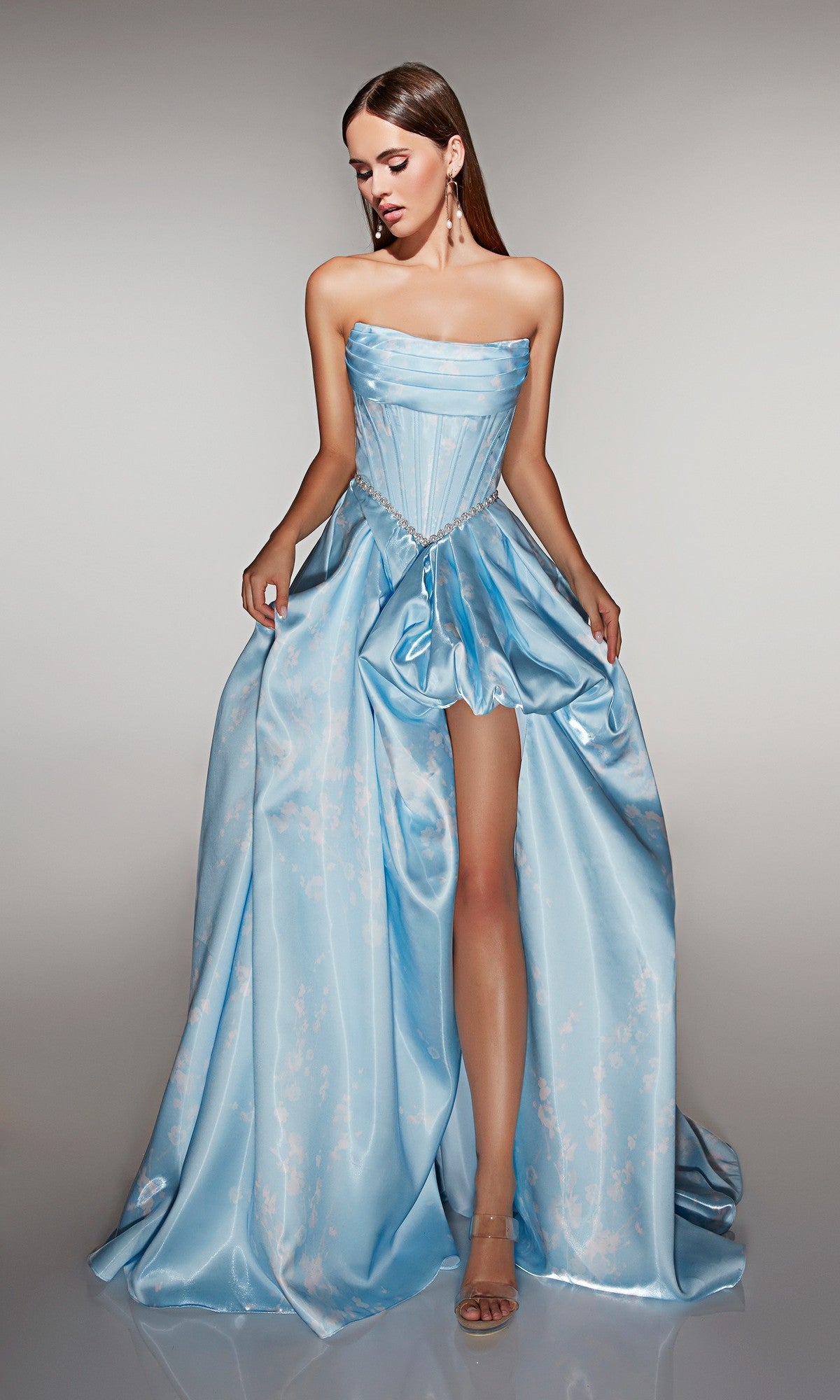 A woman stands against a neutral background wearing the Alyce 61989 Long Prom Dress, a light blue strapless satin ball gown with a corset bodice and high-leg slit.